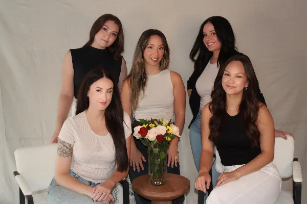 A group of five women, likely the bridal hair and makeup team, posing together with styled hair and makeup.