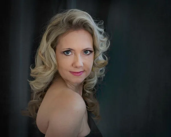 Studio portrait of a woman with blonde hair against a dark background