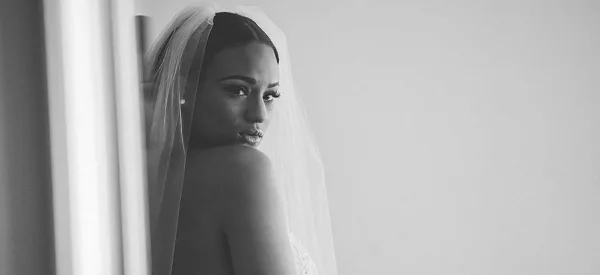 Black and white portrait of a bride wearing a veil, showing detailed makeup and hair styling.