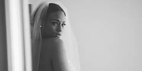 Black and white portrait of a bride wearing a veil, showing detailed makeup and hair styling.