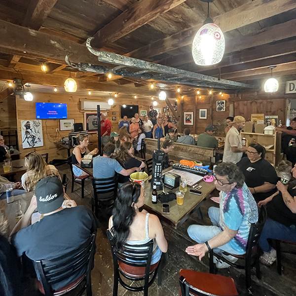 Interior view of a rustic wooden restaurant with patrons seated at tables and a canoe hanging from the ceiling.