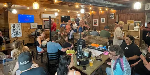 Interior view of a rustic wooden restaurant with patrons seated at tables and a canoe hanging from the ceiling.