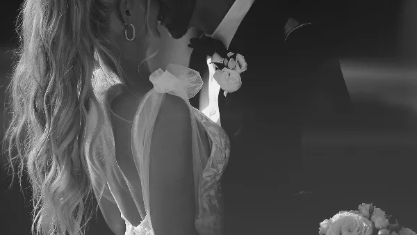 Black-and-white close-up of a bride and groom in wedding attire, with the bride's veil and the groom's boutonniere visible.