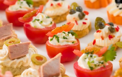 A close-up view of assorted catering appetizers including stuffed tomatoes and canapés.