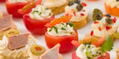 A close-up view of assorted catering appetizers including stuffed tomatoes and canapés.