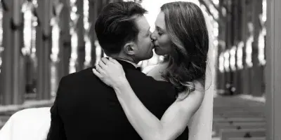 A black and white photograph of a bride and groom kissing inside a church with high vaulted ceilings.