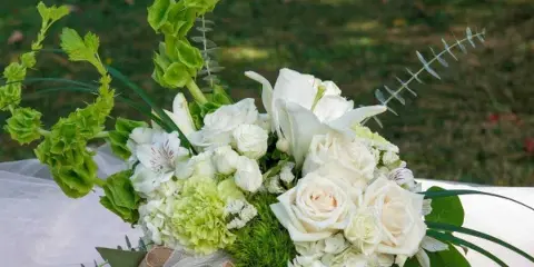White floral arrangement with roses and lilies in a glass vase