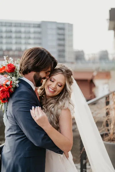 A bride and groom embracing and smiling during a wedding photo session.