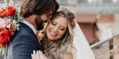 A bride and groom embracing and smiling during a wedding photo session.