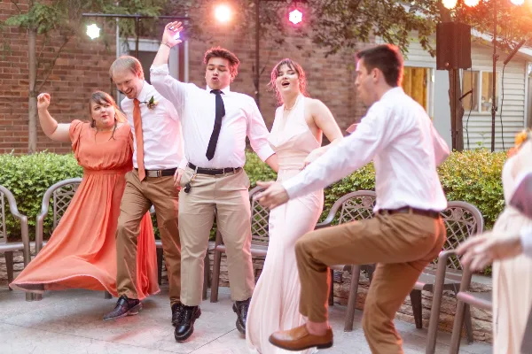 Guests dancing at an outdoor event with professional lighting and audio equipment.