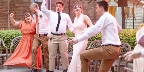 Guests dancing at an outdoor event with professional lighting and audio equipment.