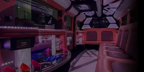 Interior view of a party bus with red leather seating, a bar counter, and purple ambient lighting.
