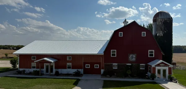 Exterior view of a red barn and silo at a farm venue