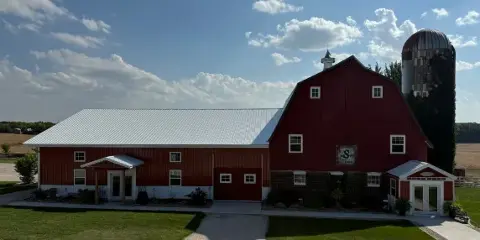 Exterior view of a red barn and silo at a farm venue