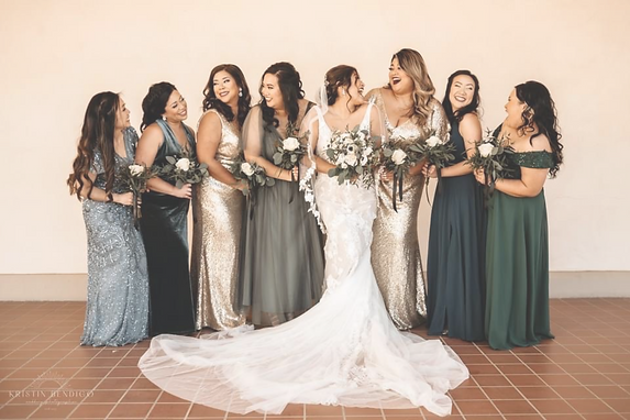 A bride and her bridesmaids standing together, showcasing styled hair and makeup.