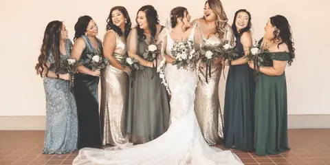 A bride and her bridesmaids standing together, showcasing styled hair and makeup.