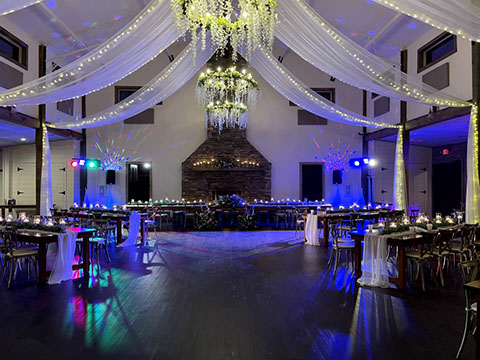 A wedding reception hall featuring a dance floor, tables, and professional stage lighting and sound equipment.