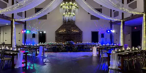 A wedding reception hall featuring a dance floor, tables, and professional stage lighting and sound equipment.
