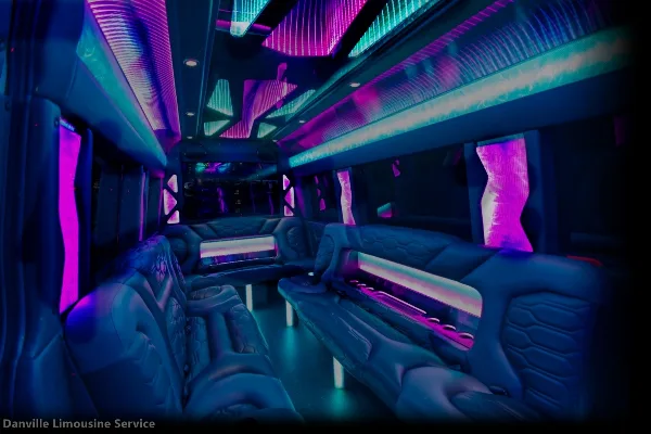 Interior view of a luxury party bus with blue and purple ambient lighting and plush leather seating.