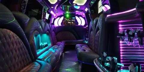 Interior view of a luxury party bus featuring plush seating, ambient LED lighting, and a champagne bucket.