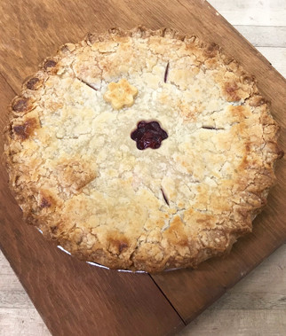 A whole baked pie with a crimped crust and a central vent hole, resting on a wooden cutting board.