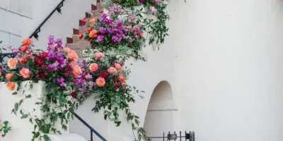 A staircase decorated with cascading floral arrangements featuring orange and purple flowers and greenery.